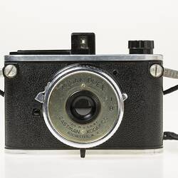 Black camera with metal trim. Metal plate around lense with text.