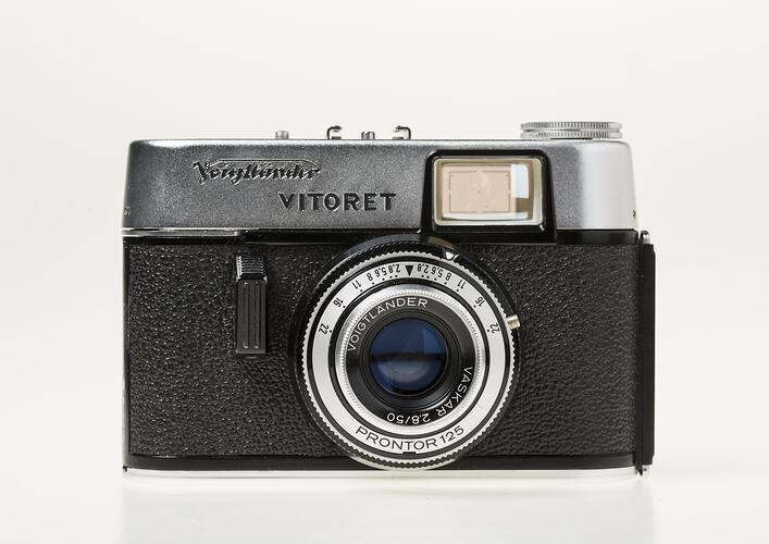 Black camera, metal trim and lens with text around. Flash top left corner.