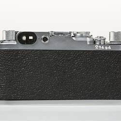 Black camera with metal trim, dials at top corners. Back view.