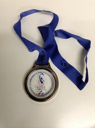 Round glass and metal medal with blue ribbon.