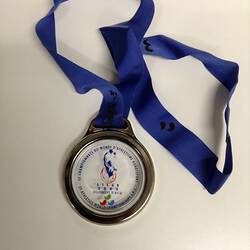 Round glass and metal medal with blue ribbon.