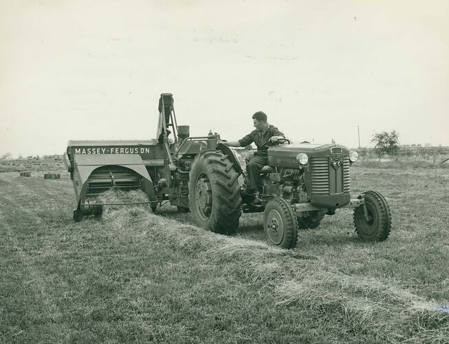 A man driving a tractor using an engine functioned Pickup Baler.