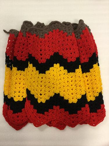 Red, yellow and black crocheted cloth, folded.