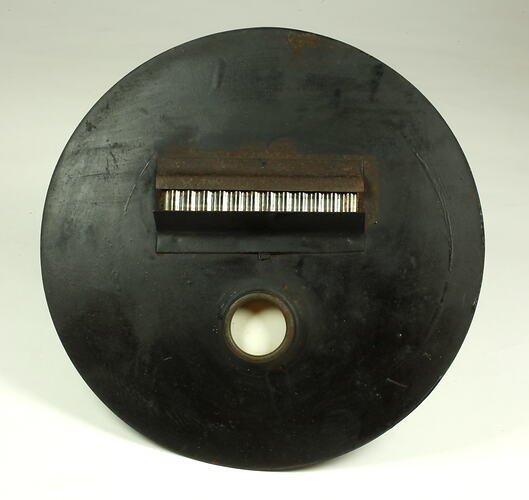 Circular metal plate painted black with rectangular opening.