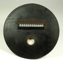 Circular metal plate painted black with rectangular opening.