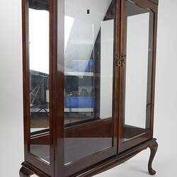 Wooden framed crystal cabinet. Glass doors and sides mirror at back. Front 3/4 view, doors closed.