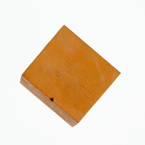 Cube-shaped wooden crystal model painted orange.