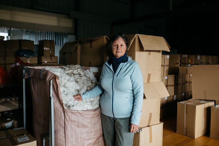 Woman standing beside wool bale.