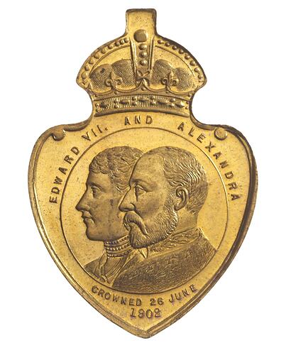 Heart with crown atop shaped  medal featuring profile of man and woman.