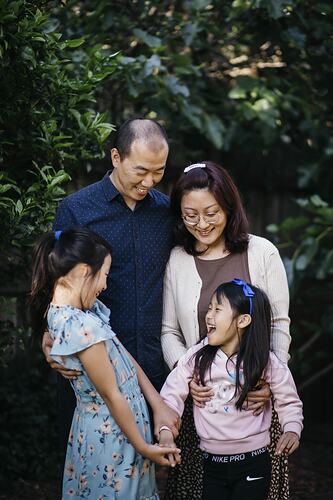 Woman, man and two girls smile in a garden setting.