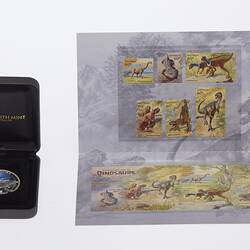 Coin with dinosaur in dark box. Stamp set at right has six separate dinosaur stamps at top. Joined set below.