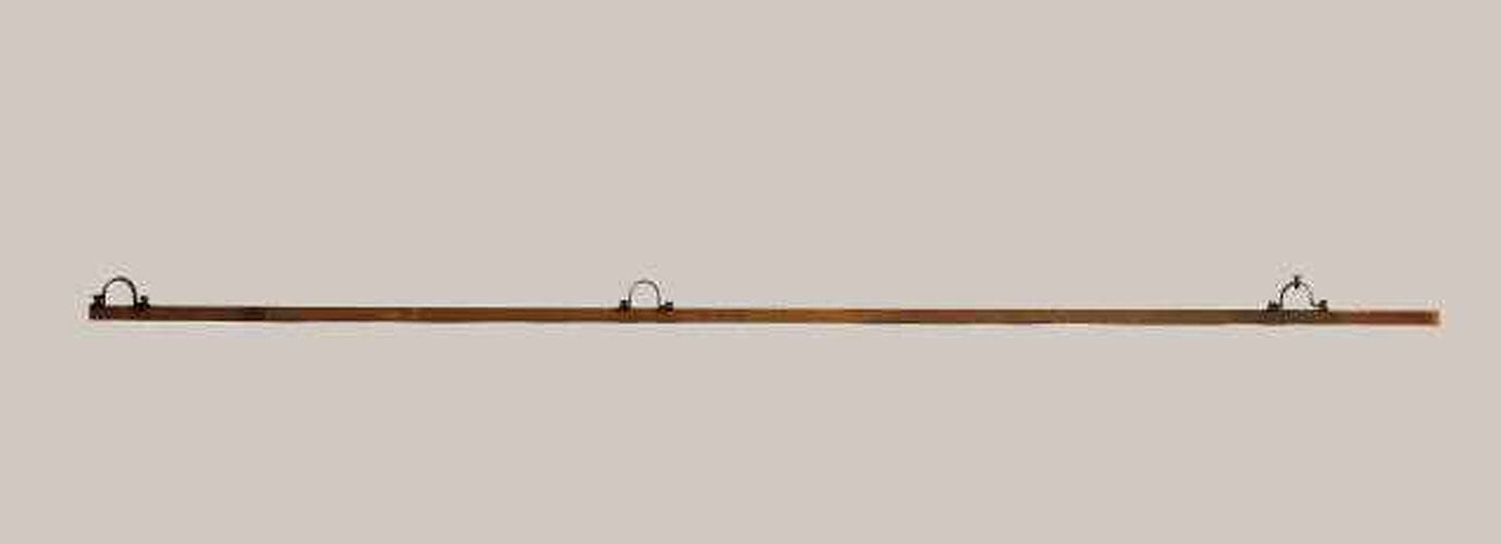 Long thin wooden rod with three metal loops.