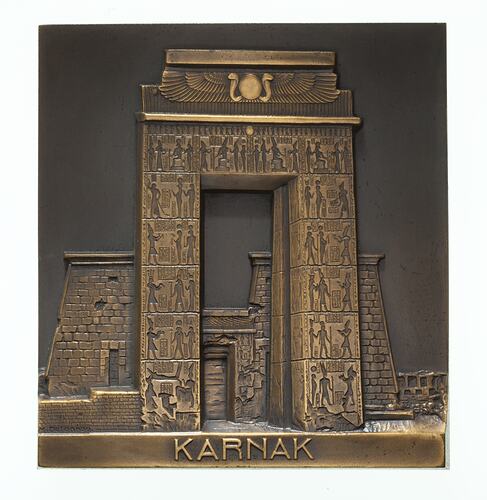 Rectangular bronze plaquette featuring decorated stone gateway.