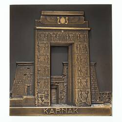 Rectangular bronze plaquette featuring decorated stone gateway.