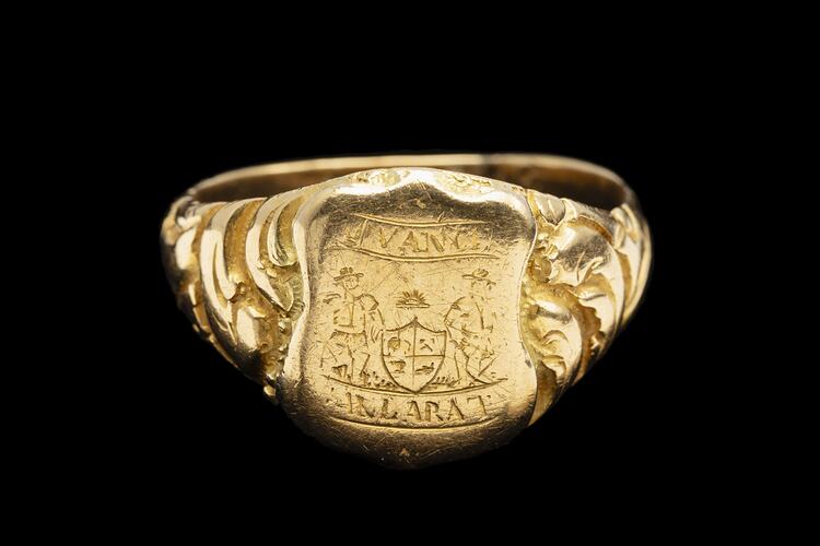 Large gold ring with central shield design featuring the words "Advance Ballaarat" and two miners leaning on a coat of arms.