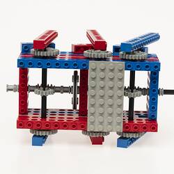 Red, blue and grey LEGO robot with three legs either side. Top view.