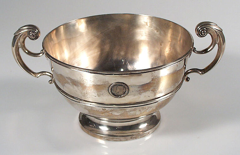 Silver rose bowl with reeded girdles, harp-shaped handles. Royal Navy crest and medal inset.