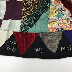 Detail of embroidered lettering on multicoloured patchwork skirt.
