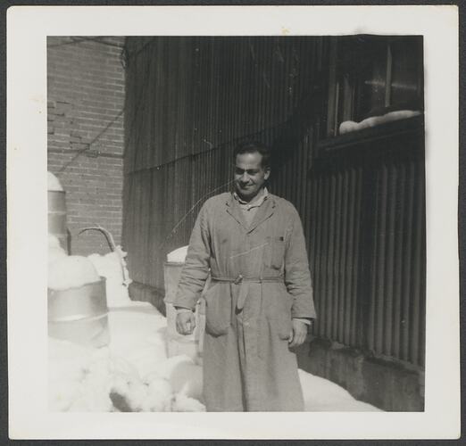 Man standing outdoors wearing long coat.