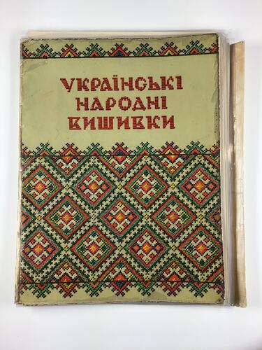 Pale green folder with colourful geometric pattern and red text on front.