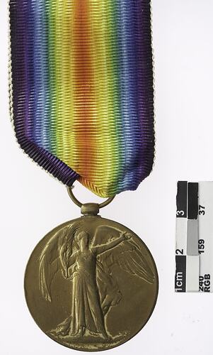 Round medal with winged woman and rainbow ribbon attached.