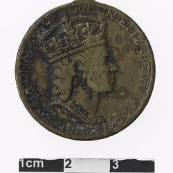 Round medal with profile of a crowned woman text surrounding, rusted on surface.