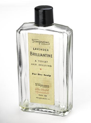 Small clear glass rectangular bottle with black lid. Printed paper label, red text. Yellow liquid in bottle.