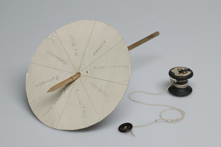 White card circle with spinner stick, cotton reel and string.
