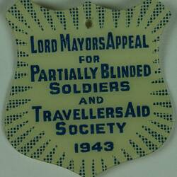 Shield shaped badge with blue text with blue pointed border.