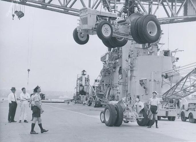 Tractor being lowered from crane onto deck.