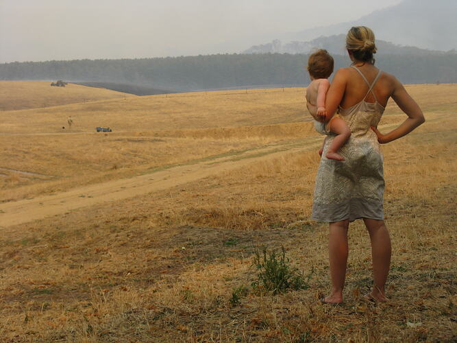 Woman and child looking across smokey landscape.