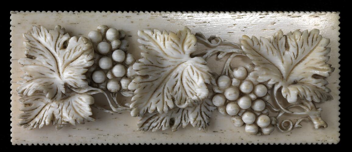 Artistic ivory box lid with leaves and grapes.