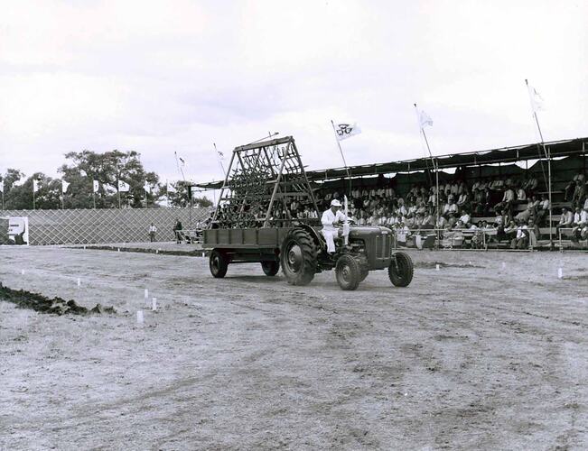 Tractor and farm equipment on display in front of grandstand.