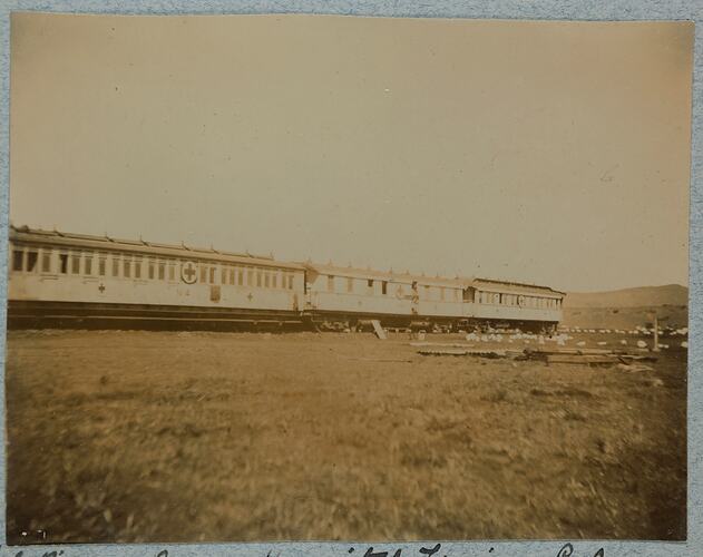 Exterior view of a train by a grassy landscape.