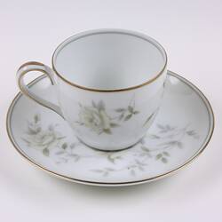 White china cup and saucer with flower pattern and gold rim.