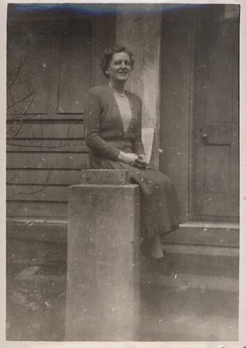 Woman seated on concrete banister.