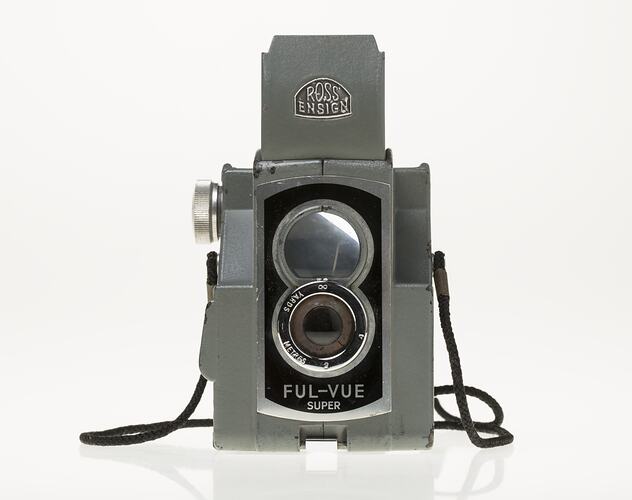 Grey metal camera with two central circles, viewfinder lens and lens. Grey hood on top.