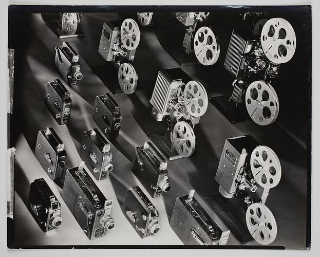 Sixteen movie cameras and projectors arranged in lines.