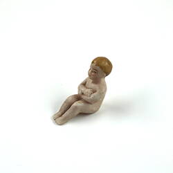 Tiny toy baby, arms crossed.