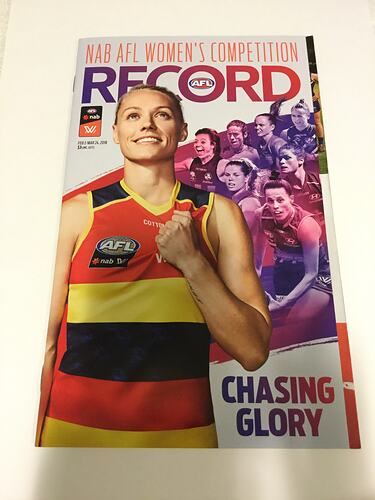 Booklet cover with female footballer wearing red, yellow and navy football jumper. Crowd behind. Text around.