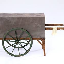 Miniature wooden coffee hand cart with two wheels two legs. Fabric cover on top.