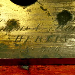 Brass apparatus on wooden base, detail of label.