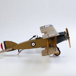 Model biplane aeroplane painted mustard brown with grey engine. Right side view.