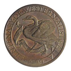 Round tarnished silver-coloured medal with swan advancing left with wings spread, text around edge.