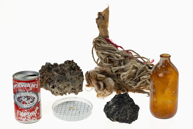 Deep sea garbage collected during the Museums Victoria and partners 'Sampling the Abyss' voyage on the RV <em>Investigator</em>: McEwans beer can, beer bottle and paint chips, rock, mop head and clinker from a steam ship.