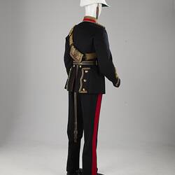 Back of navy officer's uniform with gold at cuff, sash, epaulettes, belt. Red/gold collar. White helmet.
