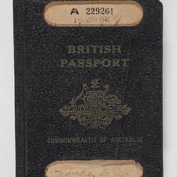 Worn navy passport with brown text and logo. Has two white labels.