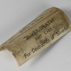 Discoloured curled bait card with printed black text.
