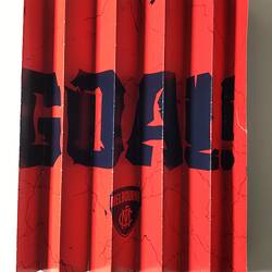 Concertina-style folded red placard with navy printed text.