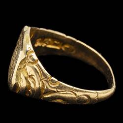 Profile of large gold ring with decorative band. Internal stamp visible.
